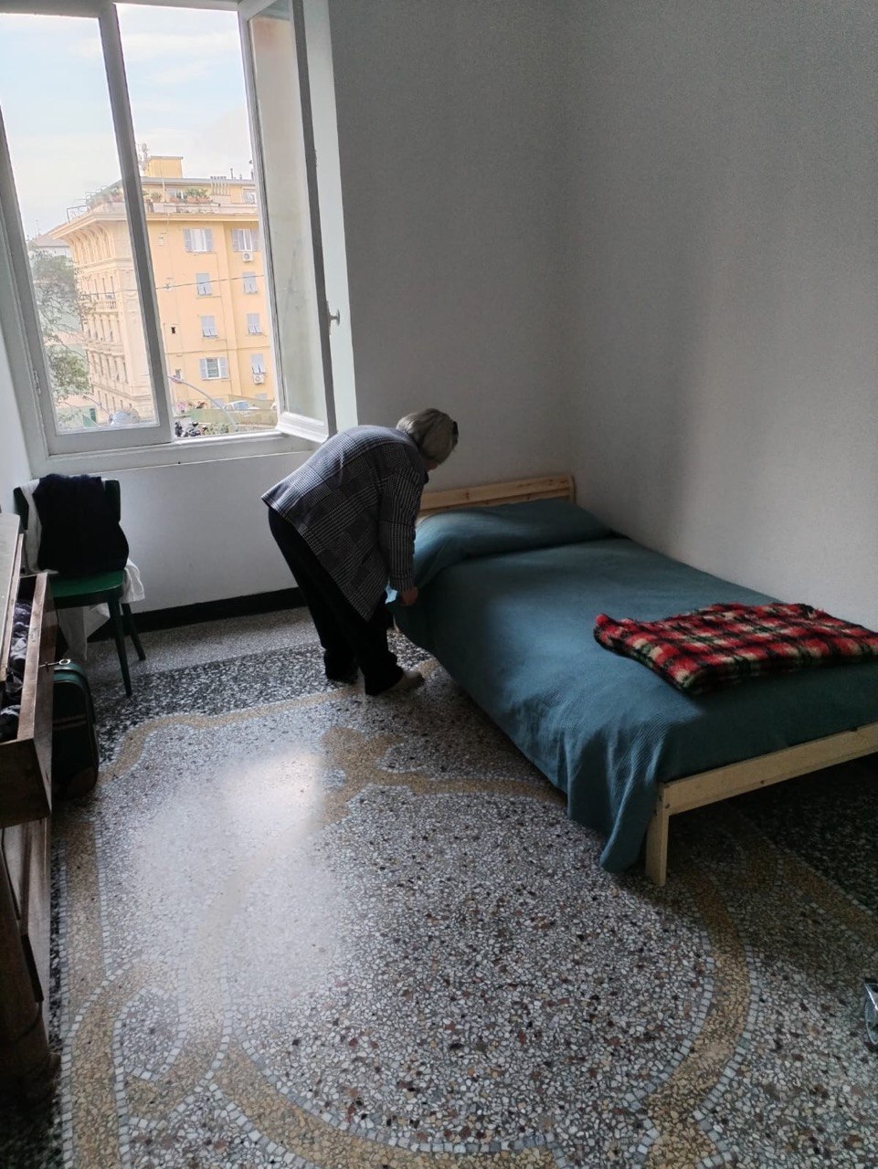 Persona che sistema il proprio letto nella camera di una casa